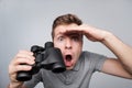 Young caucasian man looking with binocular ahead trying to see some important details. Royalty Free Stock Photo