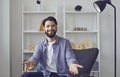 Young caucasian man looking at camera video chat with open arms in friendly welcome gesture in living room.