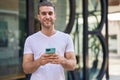 Young caucasian man miling confident listening audio message by the smartphone at street