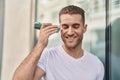 Young caucasian man miling confident listening audio message by the smartphone at street