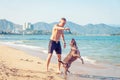 Young caucasian man playing with dog american pit bull terrier on beach. Royalty Free Stock Photo