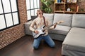 Young caucasian man playing electrical guitar on floor at home Royalty Free Stock Photo