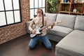 Young caucasian man playing electrical guitar on floor at home Royalty Free Stock Photo