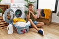 Young caucasian man putting dirty laundry into washing machine sleeping tired dreaming and posing with hands together while Royalty Free Stock Photo