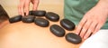 Young caucasian man receiving back massage with black stones by masseur in spa salon. A woman getting a spa treatment. Royalty Free Stock Photo