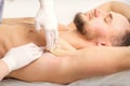 Young caucasian man receiving hair removal from his armpit in a beauty salon, depilation men underarm. Royalty Free Stock Photo