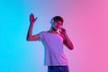 Young caucasian man`s portrait on gradient blue-pink studio background in neon light Royalty Free Stock Photo