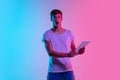 Young caucasian man`s portrait on gradient blue-pink studio background in neon light Royalty Free Stock Photo