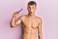 Young caucasian man shirtless holding razor scared and amazed with open mouth for surprise, disbelief face Royalty Free Stock Photo