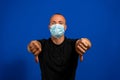 Young caucasian man with short hair wearing broken medical mask over isolated blue background being upset showing thumb Royalty Free Stock Photo