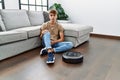 Young caucasian man sitting at home by vacuum robot thinking attitude and sober expression looking self confident Royalty Free Stock Photo
