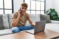 Young caucasian man smiling confident using laptop and talking on the smartphonesmartphone at home Royalty Free Stock Photo