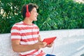 Young caucasian man smiling happy using touchpad and headphones sitting on the bench Royalty Free Stock Photo