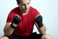 Young caucasian man in sportswear and boxing bandages sits with clenched fists, eyes are closed. Praying or despair moment, sorrow Royalty Free Stock Photo