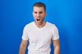 Young caucasian man standing over blue background angry and mad screaming frustrated and furious, shouting with anger Royalty Free Stock Photo