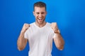 Young caucasian man standing over blue background excited for success with arms raised and eyes closed celebrating victory smiling Royalty Free Stock Photo