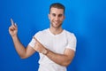 Young caucasian man standing over blue background smiling and looking at the camera pointing with two hands and fingers to the Royalty Free Stock Photo