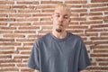 Young caucasian man standing over bricks wall making fish face with lips, crazy and comical gesture Royalty Free Stock Photo