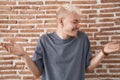 Young caucasian man standing over bricks wall smiling showing both hands open palms, presenting and advertising comparison and Royalty Free Stock Photo