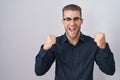 Young caucasian man standing over isolated background very happy and excited doing winner gesture with arms raised, smiling and Royalty Free Stock Photo