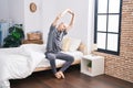 Young caucasian man stretching arms sitting on bed at bedroom Royalty Free Stock Photo