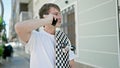 Young caucasian man talking on smartphone holding skate at street Royalty Free Stock Photo