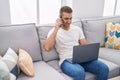 Young caucasian man talking on smartphone using laptop at home Royalty Free Stock Photo