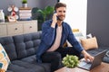 Young caucasian man talking on smartphone using laptop at home Royalty Free Stock Photo