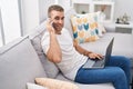 Young caucasian man talking on smartphone using laptop at home Royalty Free Stock Photo