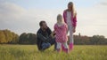 Young caucasian man talking to his daughters in the autumn evening outdoors. Father and two blonde girls dressed in pink