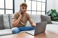 Young caucasian man using laptop talking on the smartphone at home Royalty Free Stock Photo