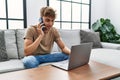 Young caucasian man using laptop talking on the smartphone at home Royalty Free Stock Photo