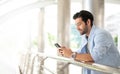 Young caucasian man using smart phone and smiling while waiting his friend at the outside. The man holding and using cellphone for Royalty Free Stock Photo