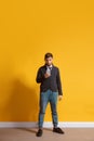 Young caucasian man using smartphone. Full body length portrait isolated over yellow background. Royalty Free Stock Photo