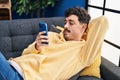 Young caucasian man using smartphone lying on sofa at home Royalty Free Stock Photo