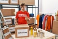 Young caucasian man volunteer holding donations box beckoning come here gesture with hand inviting welcoming happy and smiling Royalty Free Stock Photo