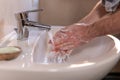 Young caucasian man washing hands rubbing with soap under running water tap in bathroom. Personal hygiene and healthcare Royalty Free Stock Photo