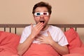 Young caucasian man watching TV at home in the bed in 3d glasses being excited and amuzed Royalty Free Stock Photo