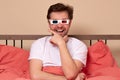 Young caucasian man watching TV at home in the bed in 3d glasses being excited and amuzed Royalty Free Stock Photo