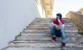 Young caucasian man talking on his smartphone, while sitting on some stairs, outdoors, with a face mask Royalty Free Stock Photo