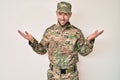 Young caucasian man wearing camouflage army uniform smiling showing both hands open palms, presenting and advertising comparison Royalty Free Stock Photo