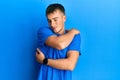 Young caucasian man wearing casual blue t shirt hugging oneself happy and positive, smiling confident Royalty Free Stock Photo