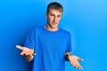Young caucasian man wearing casual blue t shirt smiling cheerful with open arms as friendly welcome, positive and confident Royalty Free Stock Photo