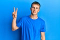 Young caucasian man wearing casual blue t shirt smiling looking to the camera showing fingers doing victory sign Royalty Free Stock Photo