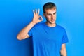 Young caucasian man wearing casual blue t shirt smiling positive doing ok sign with hand and fingers Royalty Free Stock Photo