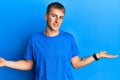 Young caucasian man wearing casual blue t shirt smiling showing both hands open palms, presenting and advertising comparison and Royalty Free Stock Photo