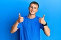 Young caucasian man wearing casual blue t shirt success sign doing positive gesture with hand, thumbs up smiling and happy Royalty Free Stock Photo