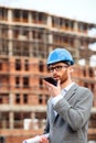 Young architect or civil engineer talking on the phone on construction site