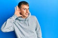 Young caucasian man wearing casual sweatshirt smiling with hand over ear listening and hearing to rumor or gossip Royalty Free Stock Photo