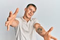 Young caucasian man wearing casual white polo looking at the camera smiling with open arms for hug Royalty Free Stock Photo